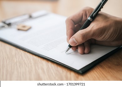 close up hand of person signing signature to contract document on the table with bank