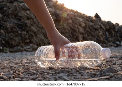 Close Up Hand Picking Up  Clear Plastic Bottle Drop On The Ground At Mountain Large Garbage Background, These Waste Come From Urban And Industrial Areas Can Not Get Rid Of