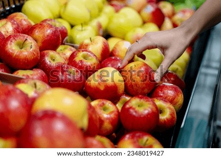 Close up hand picking red apples in the shelf.