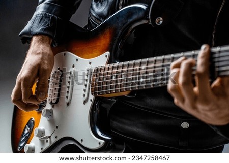 Close up hand playing electric guitar. Musician playing guitar, live music. Man playing guitar. Musical instrument. Electric guitar. Repetition of rock music band.
