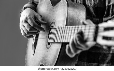 Close up hand playing guitar. Guitars acoustic. Male musician playing guitar, music instrument. Man's hands playing acoustic guitar, close up. Acoustic guitars playing. Black and white