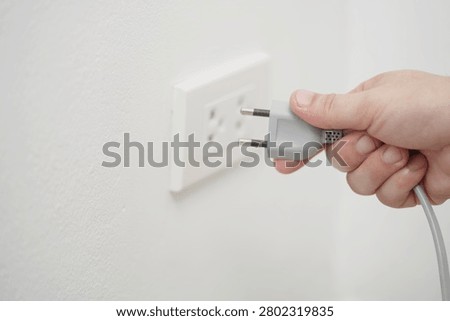 close up hand plugging adapter Electrical appliances with outlet socket plug  ,electric safety concept