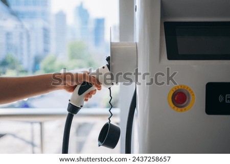 Close up hand of plugging electric car at a charging station.