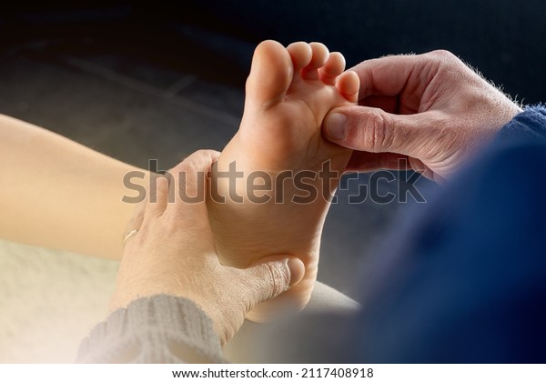 Close up hand of Podiatrist or an Orthopedic Foot\
and Ankle Specialist checking and give treatment to child with\
disorders of the foot.