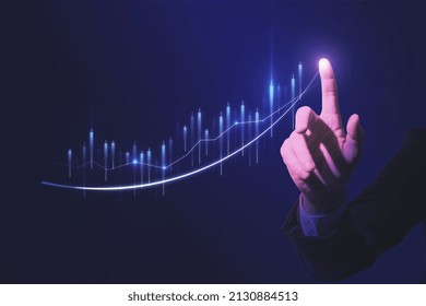 Close up of hand pointing at glowing business chart on dark blue background. Stock, market and trade concept. Double exposure - Shutterstock ID 2130884513
