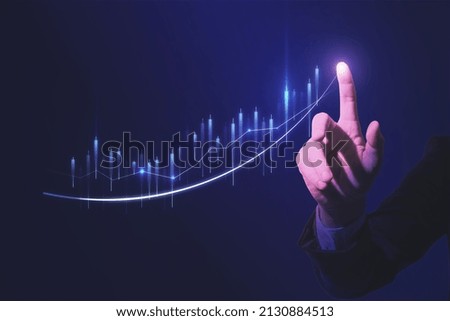 Close up of hand pointing at glowing business chart on dark blue background. Stock, market and trade concept. Double exposure
