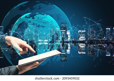 Close up of hand pointing at tablet with creative glowing globe with polygonal connections on blurry blue night city background. Big data, technology, futuristic world and business concept.