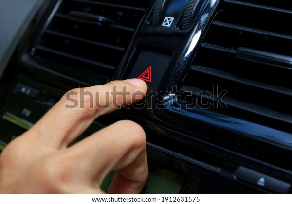 Close up hand press the emergency light in the car,\
Fingers press button.for open the contract emergency light in car.\
Emergency button press for open emergency light warning sign symbol\
out side car