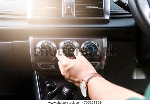 Close\
up hand pressing condition button on car\
dashboard
