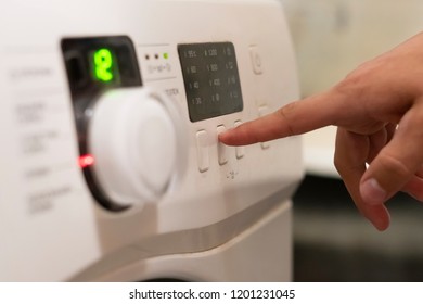 close up hand pushing the button to start the washing machine 