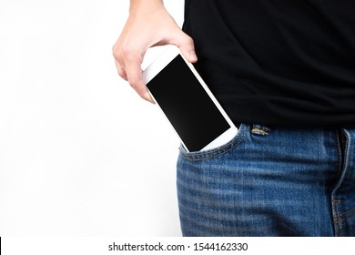 A close up of the hand is putting the smartphone into the jeans pocket on a white background. With copy space.