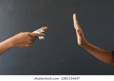 El cierre de la mano rechaza la oferta de cigarrillos diciendo que no en el fondo gris. Día Mundial Sin Tabaco.