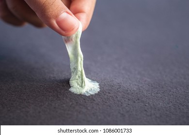 Close Up Hand Removing Sticky Chewing Gum From Black Textile Or Clothes