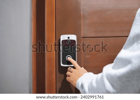 Close Up Of Hand Ringing Front Doorbell Equipped With Security Video Camera        