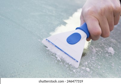 Close Up Of Hand Scraping Ice From Car Windshield With Scraper