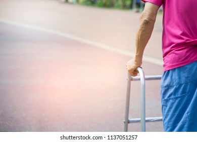 Close Up Of Hand, Senior Man 80 Year Who Has Paralysis Or Palsy Or Disability. Old Man Holding A Walker Aid Support. An Elderly Man On A Walking. Careful When He Walking Alone In Park.