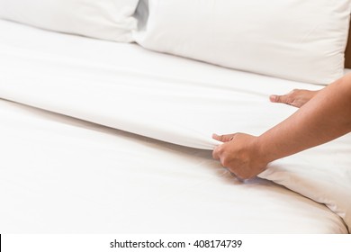 Close Up Hand Set Up White Bed Sheet In Hotel Room