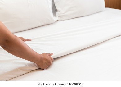 Close up hand set up white bed sheet in hotel room - Shutterstock ID 410498017