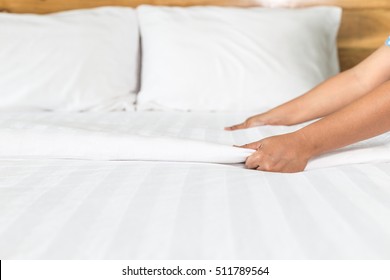 Close up hand set up white bed sheet in hotel room