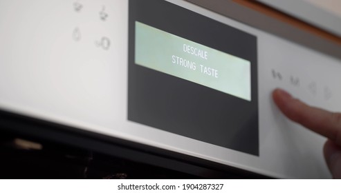 Close up of hand setting program on automatic coffee machine panel. Person selecting mode on touch panel of built-in modern coffee machine. Modern technology and kitchen appliance concept
