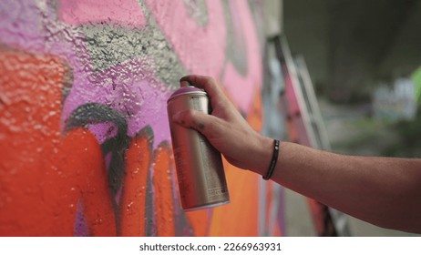 Close up hand spraying graffiti on wall