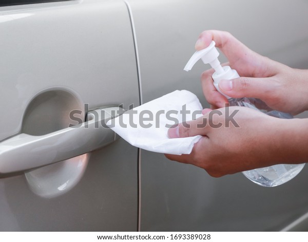 Close up of hand spraying a sanitizer from a\
bottle for disinfecting door handle of a car.\
Antiseptic,disinfection ,cleanliness and healthcare,Anti bacterial\
and Corona virus,\
COVID-19.