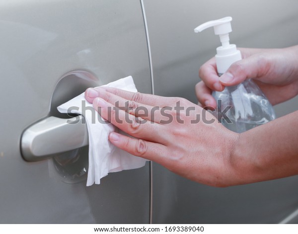 Close up of hand spraying a sanitizer from a\
bottle for disinfecting door handle of a car.\
Antiseptic,disinfection ,cleanliness and healthcare,Anti bacterial\
and Corona virus,\
COVID-19.
