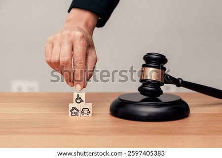 Close up of Hand stacking blocks with disability, house and car icons near judge gavel