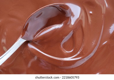 Close Up Of Hand Stirring Melted Chocolate With Spoon. Chocolate Surface, Melted Premium Chocolate Swirl. Top View.