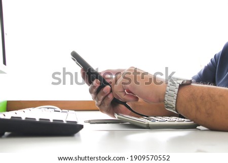 Close up hand touch smart phone with blurry keyboard of pc and working office concept. work  and Businessconcept. salaryman.