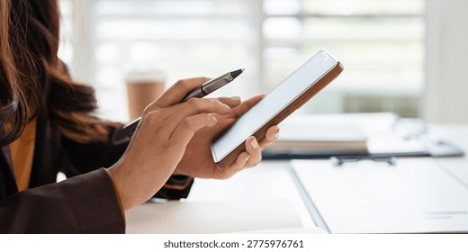 A close up hand  touching or tapping on the smartphone screen while working at office. Typing a message or searching something.