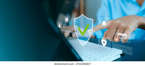 Close up of hand touching virtual security shield icon on laptop. Concept of cybersecurity, data privacy, network protection, firewall and secure online payment with holographic icons.