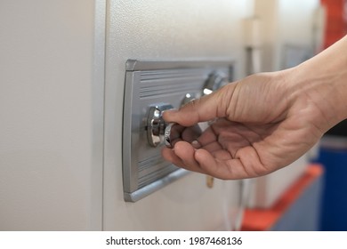 Close up of a hand unlocking a safe deposit box by turning a knob with numbers. Composite image between a hand photography - Shutterstock ID 1987468136