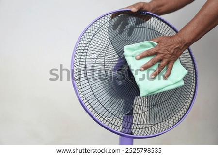 Close up hand use soft cloth to clean electric fan. Concept, Appliance maintenance and repair for long using. Clean dust on fan to stop allergy for hygiene. Chore and household keeping.               