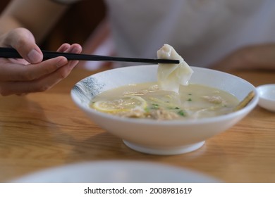 Close Up Hand Using Chopsticks Eating Wonton. Traditional Chinese Food