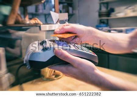Close up of a hand using a contactless credit card terminal to pay