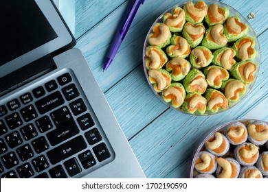 Close up of a hand using laptop computer while sitting at the kitchen table, eating cookies while working at home during lock down because corona virus 