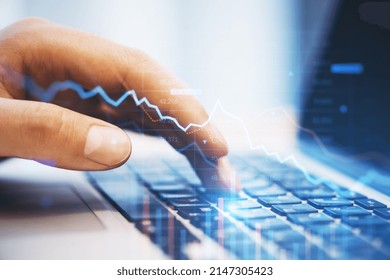 Close up of hand using laptop with falling downword forex chart on blurry background. Crisis, stock and loss concept. Double exposure