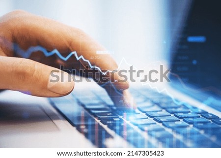 Close up of hand using laptop with falling downword forex chart on blurry background. Crisis, stock and loss concept. Double exposure