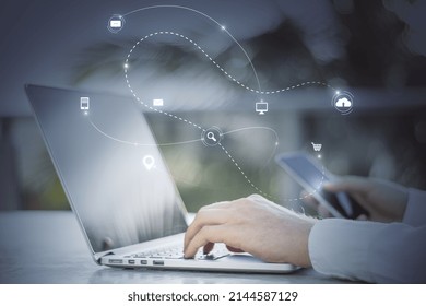 Close Up Of Hand Using Laptop Keyboard And Smartphone With Abstract SEO Search And Communication Hologram On Blurry Background. Double Exposure