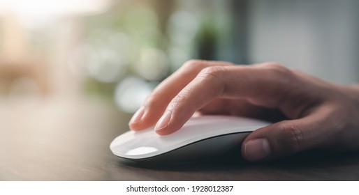 Close up of hand using on white mouse and clicking on office table. - Shutterstock ID 1928012387