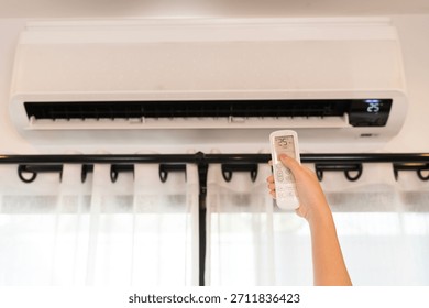 Close up hand using remote control to set air conditioner temperature indoors, creating cooling comfort and saving energy, modern home appliance technology for healthy lifestyle, climate control.