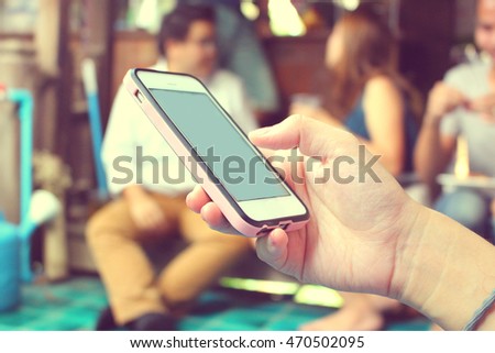 Close up of hand using smart phone in disinterest moment with talking with other people, concept of social relationship apathy and isolating using new technology and smartphone addiction