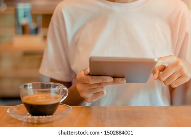 Close up hand using Tablet for internet, Modern technology and communication message with a cup of Coffee.