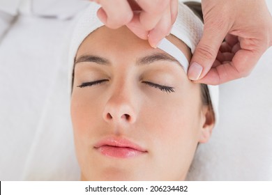 Close up of a hand waxing beautiful woman's eyebrow