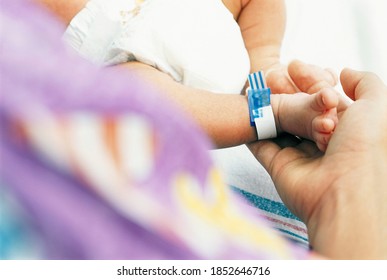 A close up of mother?s hand while holding the tiny foot of a newborn baby boy in a hospital - Powered by Shutterstock