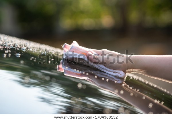 Close up of hand\
wiping water on black car