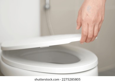 close up hand of a woman closing the lid of a toilet seat. Hygiene and health care concept.