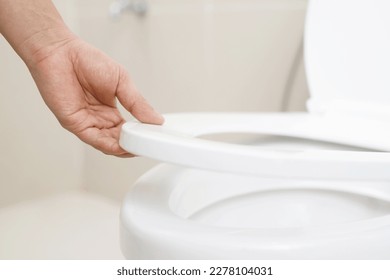 close up hand of a woman closing the lid of a toilet seat. Hygiene and health care concept. - Shutterstock ID 2278104031