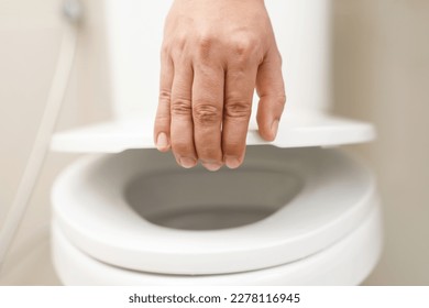 close up hand of a woman closing the lid of a toilet seat. Hygiene and health care concept. - Shutterstock ID 2278116945